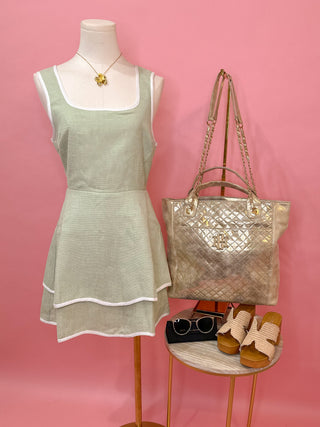 Woman wearing a light green dress with two-tiered white lining detail