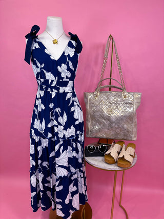  Navy base with large white floral garden print, flattering V-neckline, adjustable tie shoulder straps, smocked waist for shape, and a tiered midi-length skirt 