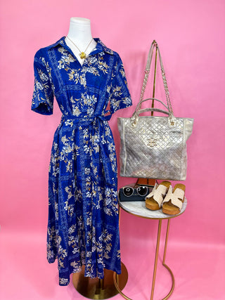 Blue floral midi dress on a woman with cream floral detail and tie at the waist
